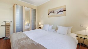 Hotelkamer met een groot bed, een kledingkast, nachtkastje met een lamp en een aan de muur hangend kunstwerk.