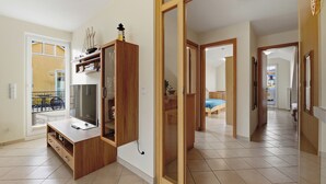 Amplia sala de estar con una unidad de entretenimiento de madera, un espejo grande y un puerta corrediza de vidrio que da a un balcón.