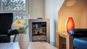 Een moderne woonkamer met een open haard, een bank, een salontafel en een vaas met bloemen.
