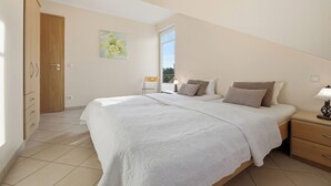 Een slaapkamer met een bed, nachtkastje en een raam.
