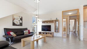 Een moderne woonkamer met een bank, salontafel, televisie en houten kasten.