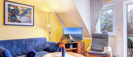 Una sala de estar moderna con un sofá azul, una mesa de centro de madera, un televisor y un cuadro en la pared.
