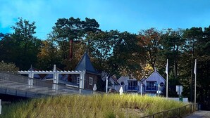 Un edificio costero frente a una playa de arena, rodeado de árboles.