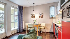 A compact kitchen with a dining area, a sofa, and a view of the outside.