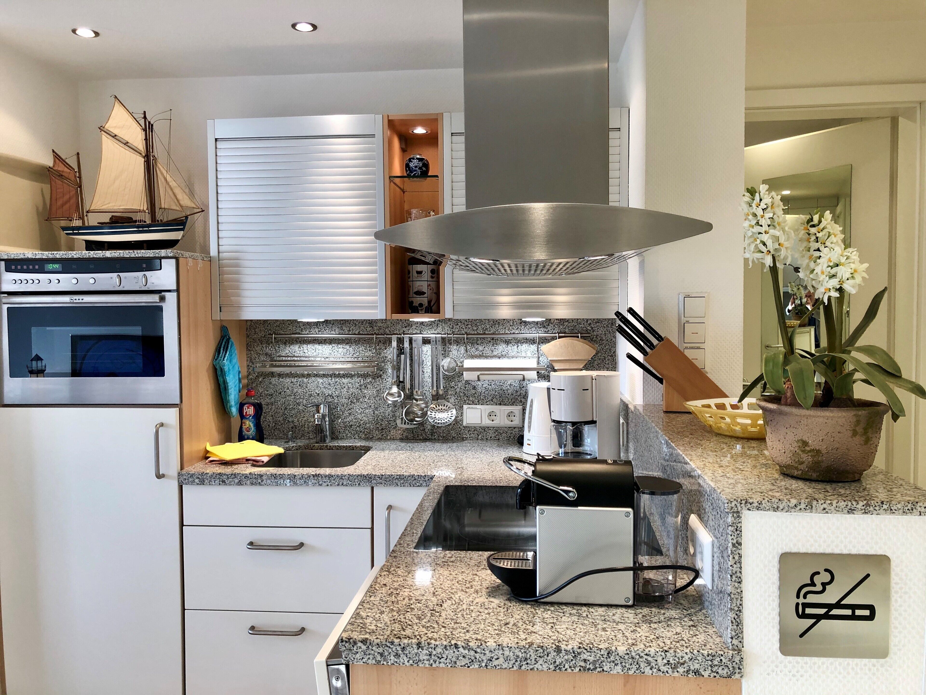 Una cocina moderna con horno empotrado, electrodomésticos de acero inoxidable, encimeras de granito y cafetera.