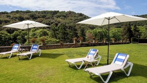 A grassy outdoor area with several lounge chairs and white umbrellas. - Charming Mediterranean villa with pool near Barcelona (Arenys de Munt)