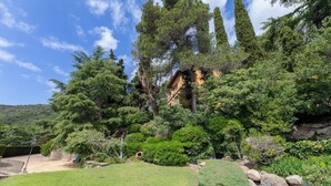 A lush garden with a variety of trees and shrubs, a well-maintained lawn, and a rocky outcrop. - Charming Mediterranean villa with pool near Barcelona (Arenys de Munt)