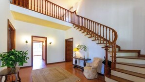 A spacious living area with a wooden staircase, a rug, a chair, and a table with a lamp. - Charming Mediterranean villa with pool near Barcelona (Arenys de Munt)
