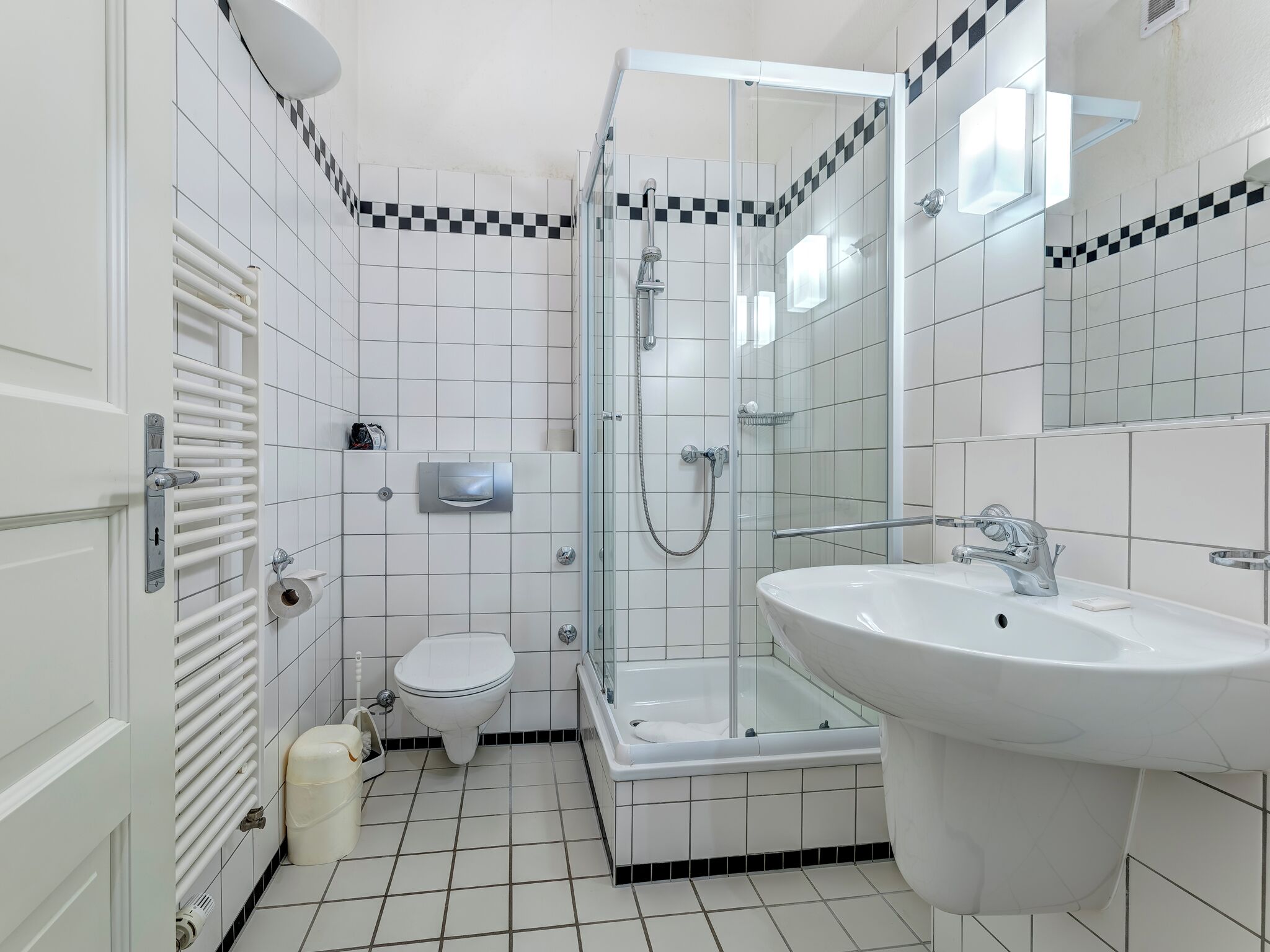 A modern bathroom with a glass-enclosed shower, a toilet, and a sink.