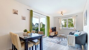 A modern living room with a dining area, a TV, and a sofa.