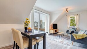 A modern loft apartment with a dining area, a living room, and a TV on a wooden stand. - Vacation home Döhner Whg. 04 in Zinnowitz with balcony and 500 m to the sandy beach (Zinnowitz)