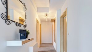 A hallway with a wooden floor, a white wall, and a black metal mirror with a decorative frame. - Vacation home Döhner Whg. 04 in Zinnowitz with balcony and 500 m to the sandy beach (Zinnowitz)