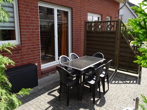 Enjoy an outdoor space with a table for four, surrounded by lush greenery and a secure entrance.