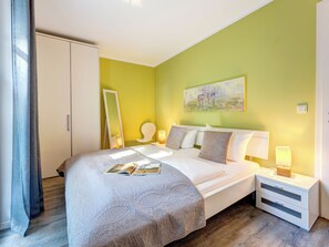 Een hotelkamer met een bed, nachtkastjes, een spiegel en een schilderij aan de muur.
