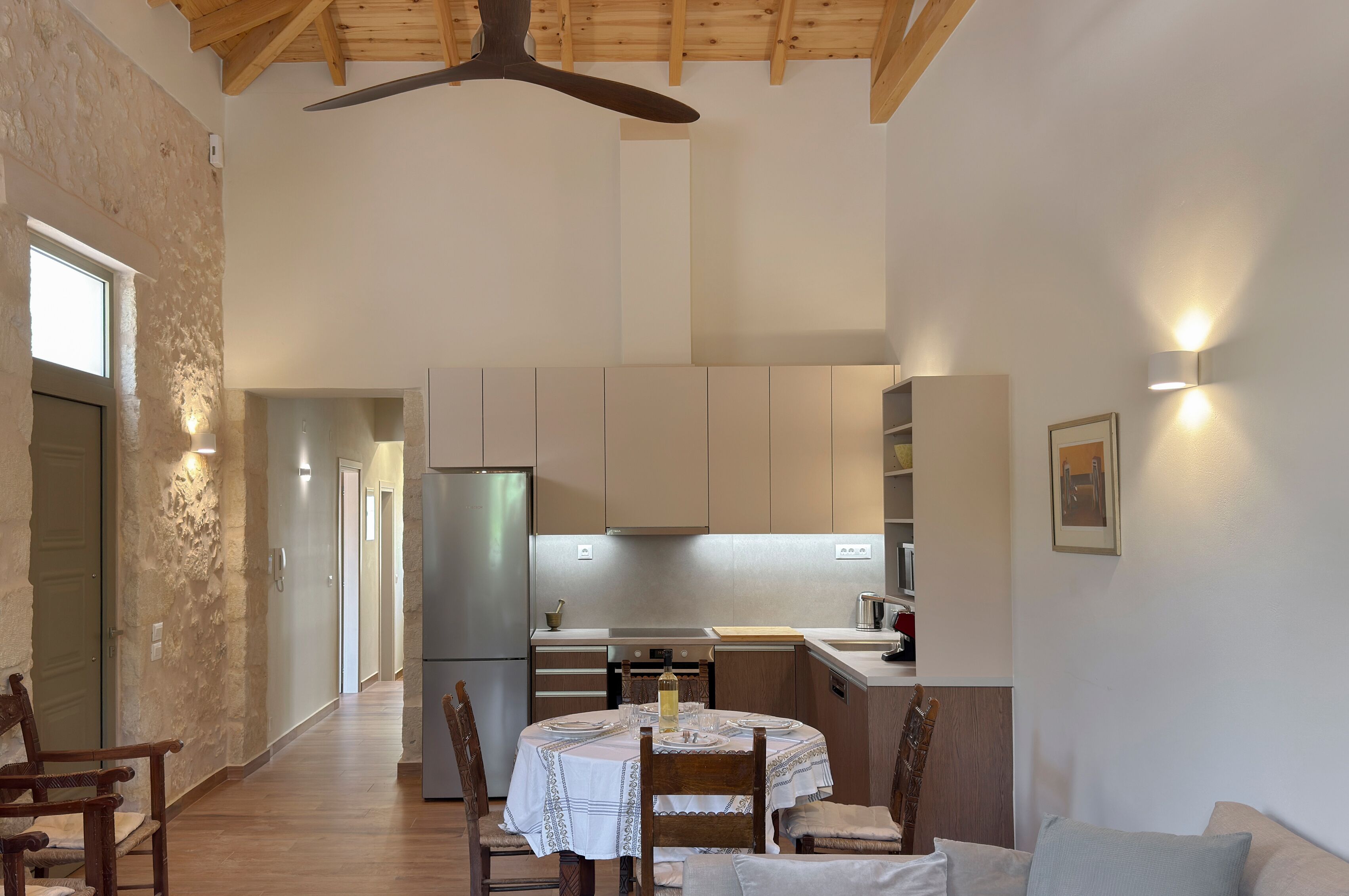 A spacious kitchen with modern appliances, a dining area with a round table, and a wooden ceiling.