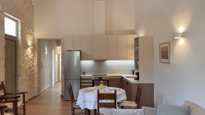 Une cuisine spacieuse dotée d’appareils électroménagers modernes, un coin repas avec une table ronde et un plafond en bois.