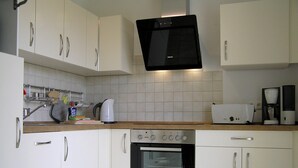 A kitchen with white cabinets, a built-in oven, a microwave, and a coffee maker. - House Vincent, apartment 1 in Zinnowitz: 62 m² for 4 with terrace and WLAN (Zinnowitz)