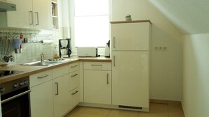 A compact kitchen with white cabinets, a built-in oven, a coffee maker, and a toaster. - House Vincent, apartment 3 in Zinnowitz with balcony, WLAN and 4 beds (Zinnowitz)