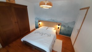 Un dormitorio con una cama de madera, una mesita de noche, una lámpara de pared y una puerta.