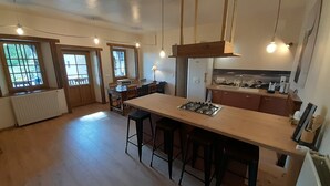Una cocina amplia con una isla central, suelo de madera e iluminación colgante.
