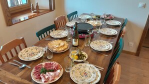 Una mesa de madera dispuesta para una comida, con platos, cubiertos, vasos y una botella de vino.