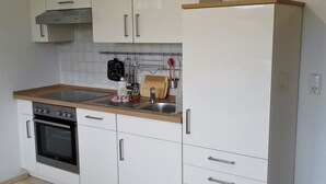 A kitchen with white cabinets, a stainless steel oven, a sink, and a wooden countertop. - House Vincent, apartment 5 in Zinnowitz: terrace, WLAN & close to the beach (Zinnowitz)