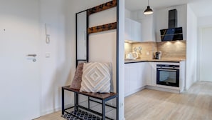 A modern kitchen with a built-in oven, a coffee maker, and a hanging light fixture. - Bernsteinquartier, Whg. 02.25 in Kölpinsee - Stylish 2-room oasis near the Baltic Sea (Kölpinsee)