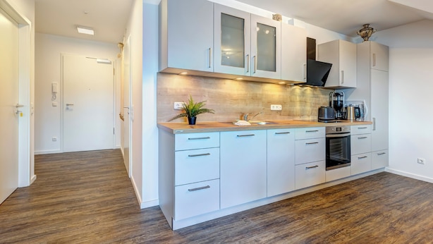 A modern kitchen with white cabinets, a wooden countertop, and a built-in oven.