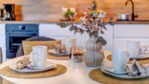 A dining table set with white plates, cups, and a vase with flowers. - Bernsteinquartier, Mister Bernstein, Whg. 01.08 in Kölpinsee - pure relaxation (Kölpinsee)