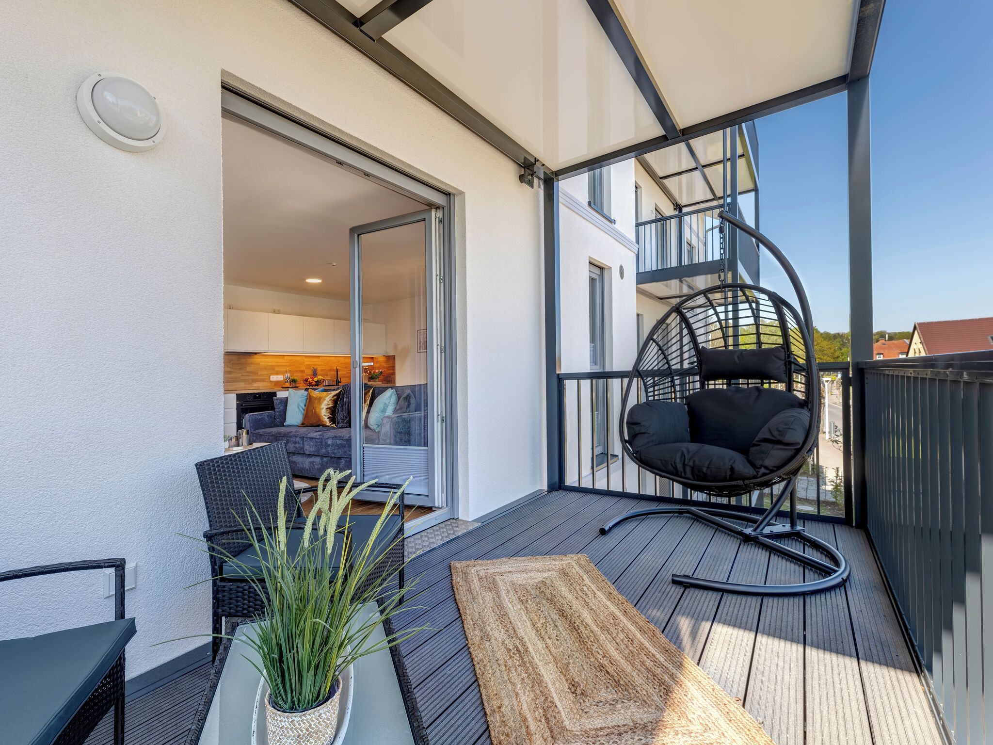 A balcony with a black chair, a table, and a potted plant.