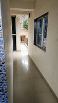 A corridor with a window on the right, a door at the end, and a tiled floor.