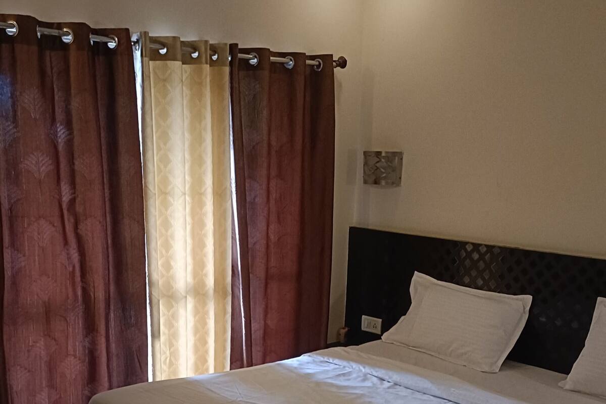 Un dormitorio con una cama grande, cabecero oscuro y paredes color beige.
