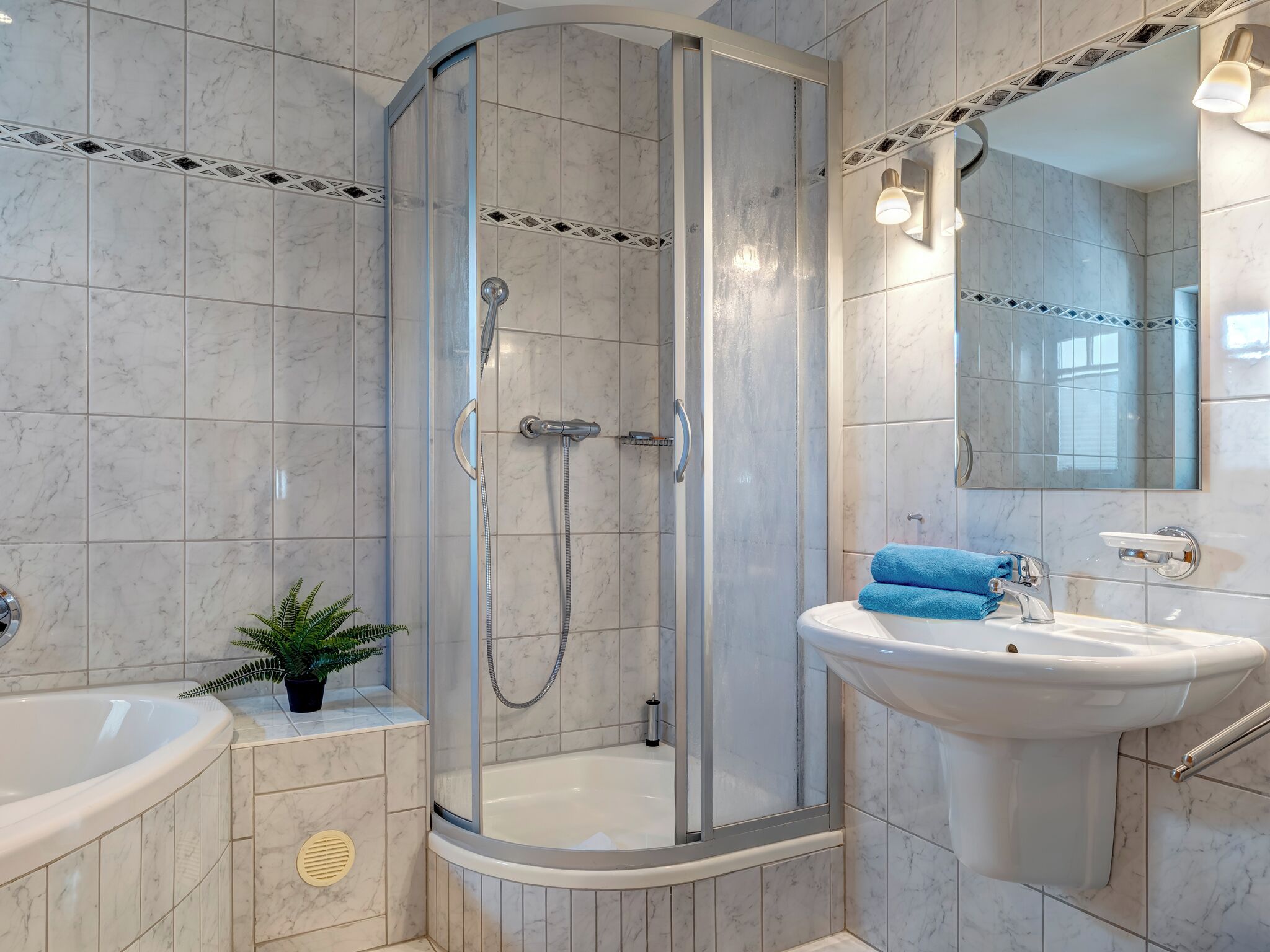 A modern bathroom with a glass-enclosed shower, a white sink, and a mirror above the sink.