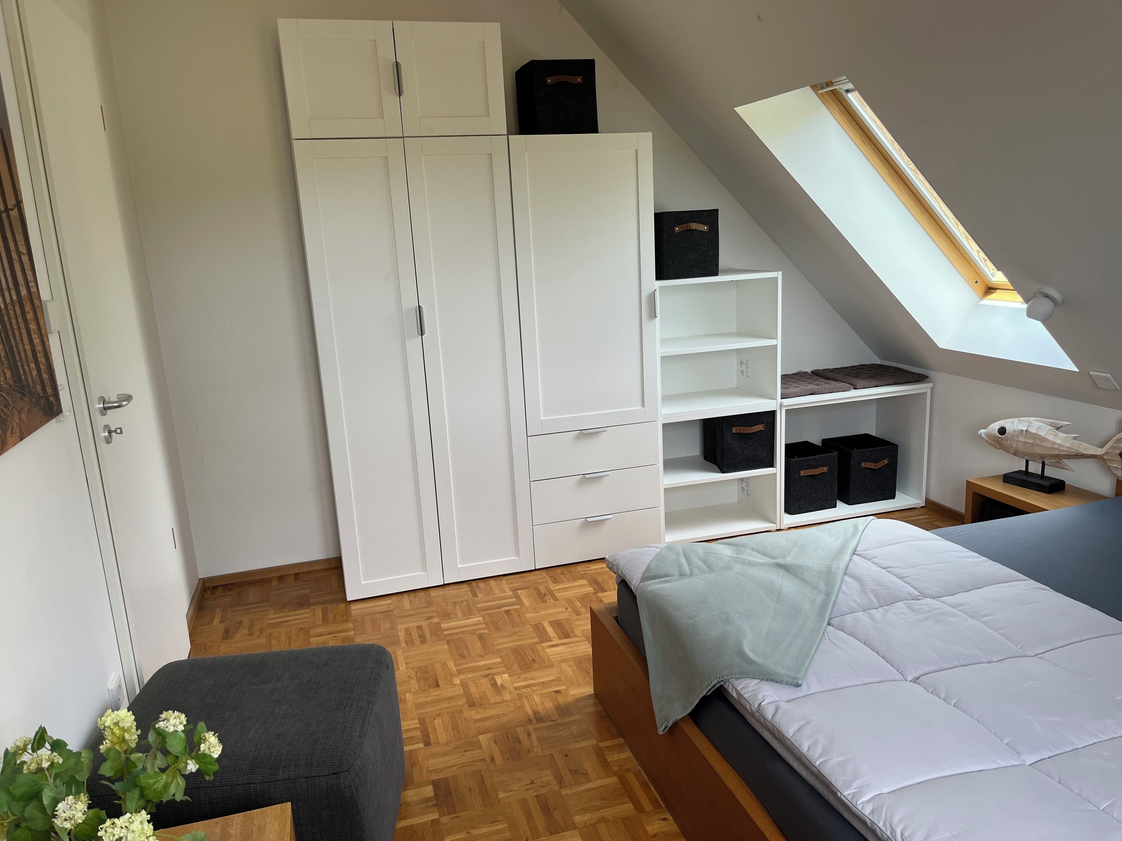 Une chambre à coucher avec un lit, une armoire, un bureau et une lucarne.