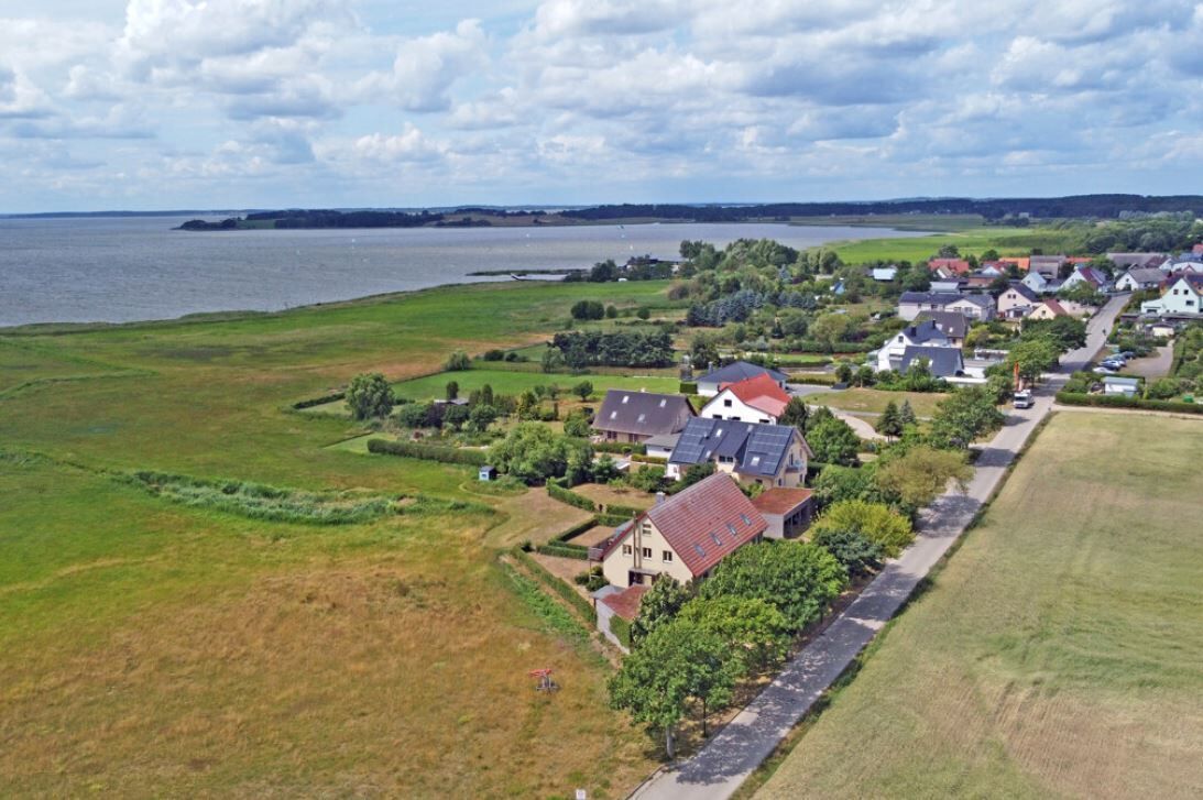 A residential area with houses, a road, and a body of water in the background.
