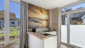 Una cuina moderna amb una finestra gran, vistes a l'exterior i un quadre a la paret.