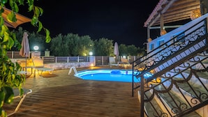 A wooden deck with a swimming pool, lounge chairs, and a staircase with wrought iron railings. - Amalia Villa with Private Pool (Mylopotamos)