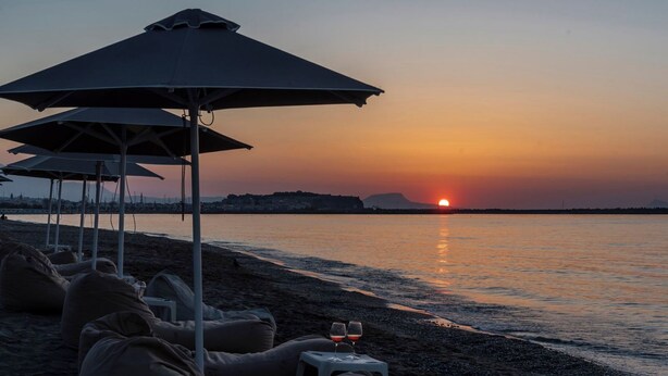 A beach with umbrellas and lounge chairs, a sunset, and a calm sea. - Amalia Villa with Private Pool (Mylopotamos)