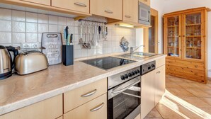 A kitchen with wooden cabinets, a stainless steel stove, a sink, and a microwave. - Ostseequartett, Whg. 24 Strand-im-Schuh: 55 m² for 4 persons with balcony (Zinnowitz)