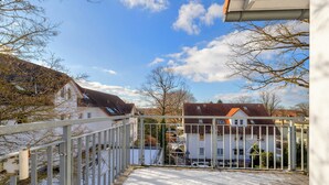 A balcony with a metal railing overlooking a residential area with houses and a clear sky. - Ostseequartett, Whg. 24 Strand-im-Schuh: 55 m² for 4 persons with balcony (Zinnowitz)