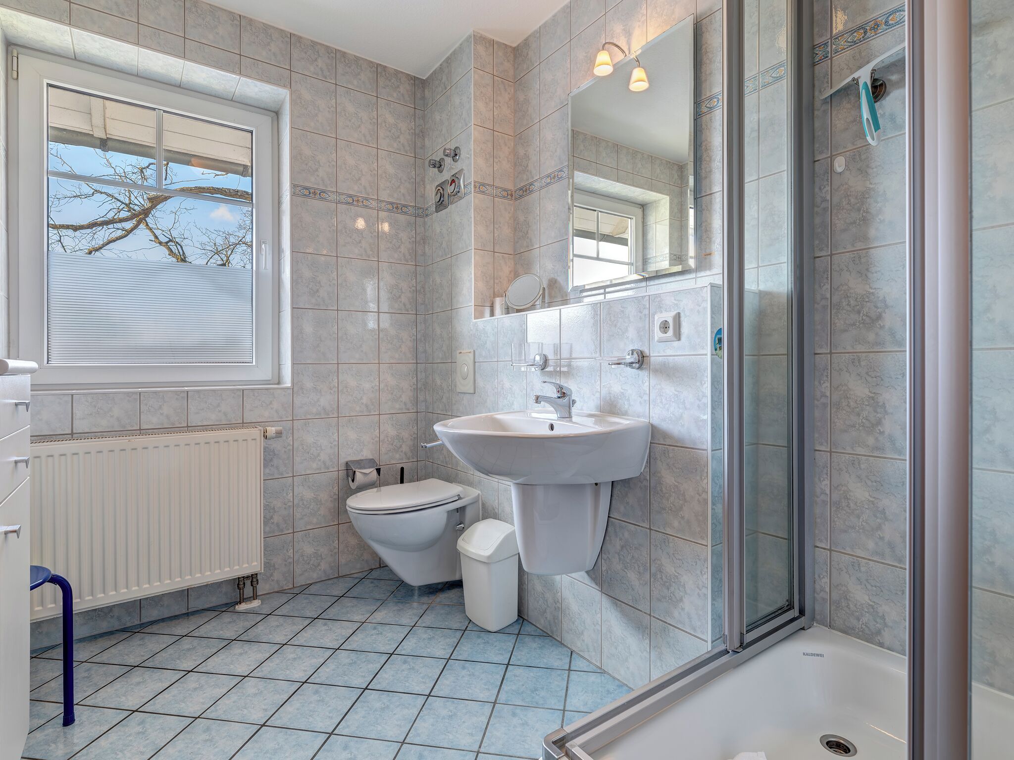 A modern bathroom with a large window, a bathtub, a sink, and a toilet.