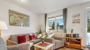 A living room with a sofa, armchairs, a coffee table, a bookshelf, and a large map on the wall. - Ostseequartett, Whg. 24 Strand-im-Schuh: 55 m² for 4 persons with balcony (Zinnowitz)