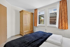 A bedroom with a bed, a wardrobe, and a window with curtains.