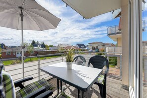 A balcony with a table, chairs, and a potted plant.