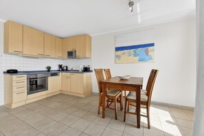 A modern kitchen with wooden cabinets, a dining table, and chairs.
