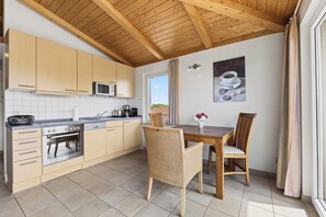 A kitchen with wooden cabinets, a microwave, an oven, and a dining area with a table and chairs.