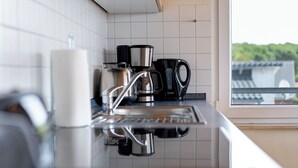 A kitchen with a coffee maker, a kettle, and a coffee pot on the counter. - Am Sonnenblick Whg. 5: Apartment with balcony near the sandy beach in Heringsdorf (Heringsdorf)