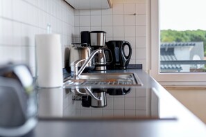 Eine Küche mit Kaffeemaschine, Wasserkocher und Kaffeekanne auf der Arbeitsfläche.