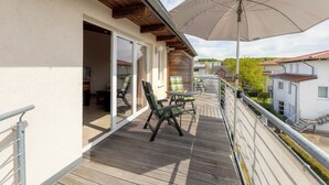 A balcony with outdoor furniture, a large umbrella, and a view of the surrounding buildings. - Am Sonnenblick, Whg. 6:41 m² apartment with balcony, WLAN & close to the beach (Heringsdorf)