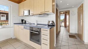 A kitchen with wooden cabinets, a stainless steel oven, a microwave, and a window with a view. - Am Sonnenblick, Whg. 6:41 m² apartment with balcony, WLAN & close to the beach (Heringsdorf)